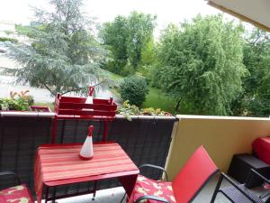马孔Appartement cosy 4 personnes的阳台的庭院配有红色的桌椅