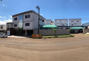 伊茹伊Apart-Hotel Ijuí的街道旁一座带两把绿色遮阳伞的建筑