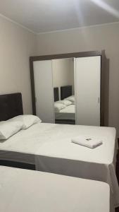 伊茹伊Apart-Hotel Ijuí的一间带镜子的卧室和一张带白色毯子的床