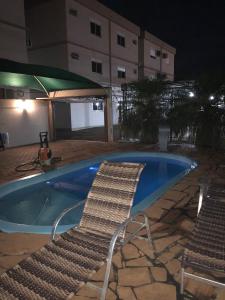 伊茹伊Apart-Hotel Ijuí的一把椅子和一个晚上的游泳池