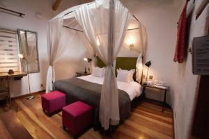 库斯科ARQUEOLOGO EXCLUSIVE SELECTION - Casa Peralta的一间卧室配有一张带粉红色凳子的天蓬床。