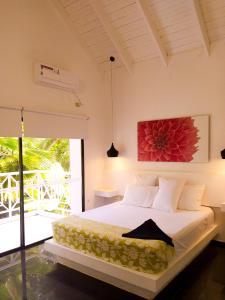 圣安德烈斯Casa de las Flores tropical的卧室配有一张挂着红色花卉画的床铺。