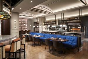 迈阿密Loews Coral Gables Hotel的餐厅设有蓝色酒吧,配有桌椅