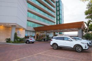 瓜亚基尔瓜亚基尔机场假日酒店的两辆汽车停在大楼前的停车场