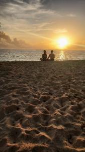 Santa Monica3B Beach Resort Alegria的两人坐在海滩上欣赏日落