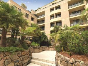 悉尼悉尼库吉海阿迪纳公寓式酒店的一座石头墙、棕榈树和人行道的建筑