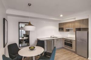 悉尼悉尼库吉海阿迪纳公寓式酒店的带桌椅的厨房和带水槽的厨房