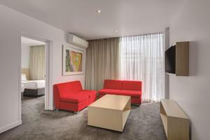 墨尔本墨尔本港区旅程住宿酒店的客厅配有2把红色椅子和电视