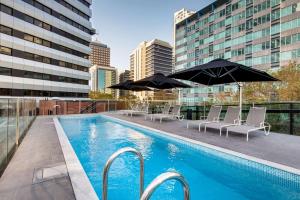 悉尼悉尼北部维伯酒店的大楼内一个带椅子和遮阳伞的游泳池