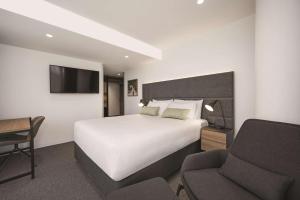 墨尔本Vibe Hotel Melbourne的酒店客房配有一张床、一张桌子和一把椅子。