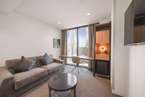 墨尔本Vibe Hotel Melbourne的客厅配有沙发和桌子