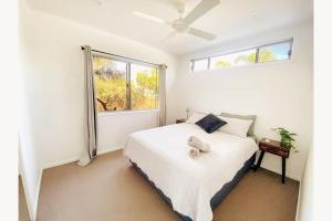 库鲁姆海滩Beach House with spa among the trees Coolum Beach的卧室配有白色的床和窗户。