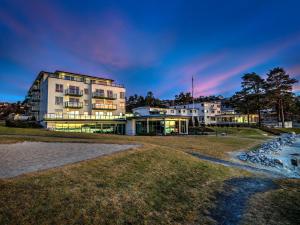 弗维克Strand Hotel Fevik - by Classic Norway Hotels的水体岸边的建筑物