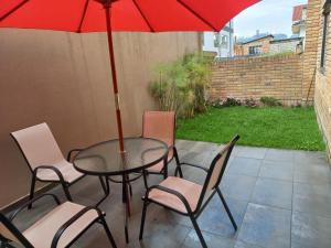 昆卡Departamento excelente ubicación con parqueo的庭院里配有桌椅和红伞