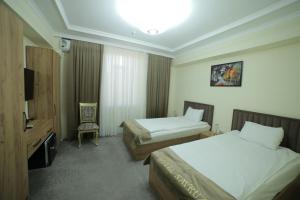 乌尔根奇HOTEL NAVRUZ的酒店客房设有两张床和电视。