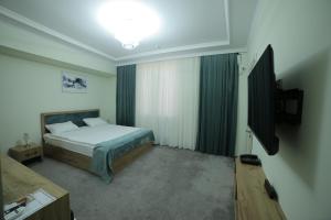 乌尔根奇HOTEL NAVRUZ的一间卧室配有一张床和一台平面电视