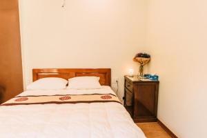 顺化Chi Homestay #4的一间卧室配有一张带木制床头板和一张桌子的床。