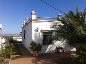 贝赫尔-德拉弗龙特拉El Matorral Chalet的前面有棕榈树的白色房子