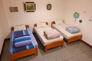 Minxiong卡洛斯民宿的客房内的三张床和一把椅子