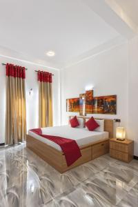 丹不拉White Land City Hotel的一间卧室配有一张带红色枕头的大床