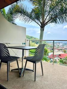 卡塔海滩山海景观豪华公寓的棕榈树阳台的一张桌子和两把椅子