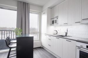 劳马Rauma City Center Studios的厨房配有白色橱柜和黑色台面