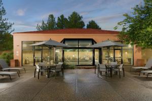 阿尔伯克基Courtyard by Marriott Albuquerque Airport的一个带桌椅和遮阳伞的户外庭院。