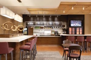 夏洛特夏洛特机场北部万怡酒店的厨房配有带椅子的酒吧和一台电视