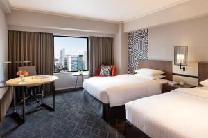 大阪新大阪车站万怡酒店的酒店客房设有两张床、一张桌子和一个窗户。
