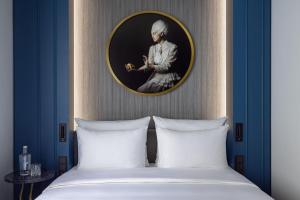 柏林Hotel Luc, Autograph Collection的卧室,配有一张床和一张女人的肖像
