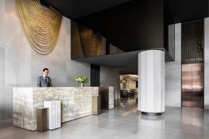 墨尔本Melbourne Marriott Hotel Docklands的站在大堂柜台后面的人