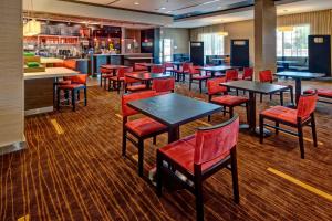 韦斯特伯里韦斯特伯里长岛万怡酒店的一间带桌子和红色椅子的餐厅和一间酒吧
