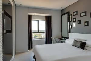 比勒陀利亚比勒陀利亚门林普罗蒂亚火与冰万豪酒店的卧室设有一张白色大床和一扇窗户。