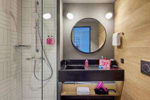 科隆Moxy Cologne Muelheim的浴室配有盥洗盆和带镜子的淋浴