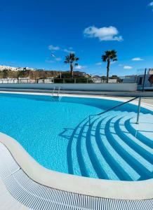 波多黎各Peace and View Apartment Puerto Rico的一座拥有蓝色海水和棕榈树的游泳池