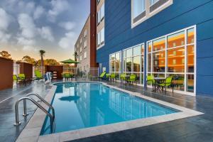 格尔夫波特SpringHill Suites by Marriott Gulfport I-10的一座带桌椅的游泳池位于酒店大楼旁