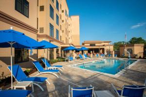 彭萨科拉Residence Inn by Marriott Pensacola Airport/Medical Center的一座带椅子和遮阳伞的游泳池位于一座建筑旁边
