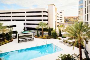 坦帕AC Hotel by Marriott Tampa Airport的享有带游泳池和棕榈树的建筑的空中景致
