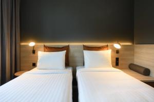 斯图加特Moxy Stuttgart Feuerbach的配有白色床单的酒店客房内的两张床