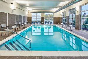 奥尔巴尼Residence Inn by Marriott Albany Airport的大楼内一个带桌椅的游泳池