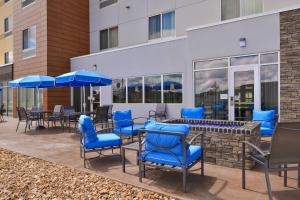 沃伦斯堡Fairfield Inn & Suites by Marriott Warrensburg的一个带蓝色桌椅和遮阳伞的庭院