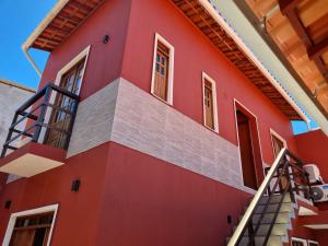 普拉亚多Suíte na vila de Praia do Forte的一座红色的房子,旁边设有楼梯
