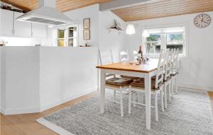 维斯特索马肯3 Bedroom Nice Home In Aakirkeby的白色的厨房配有木桌和椅子