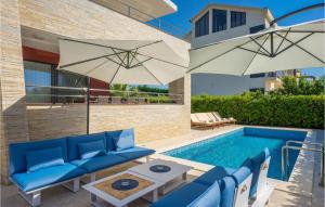 扎顿Awesome Home In Zaton With Wifi, Outdoor Swimming Pool And Heated Swimming Pool的一个带蓝色家具和遮阳伞的游泳池