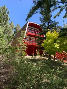 大熊湖Maison Solange-Red Barn Farmhouse Style- Moonridge的树中间的红色建筑,设有红色阳台