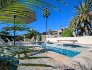 特乌拉达Lovely Appartment 'Solana' with big garden, nice pool的一个带长凳和棕榈树的游泳池