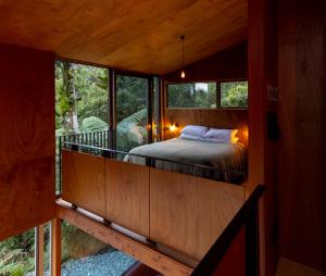 普纳凯基Punakaiki Forest Retreat的树屋的卧室,阳台上设有一张床
