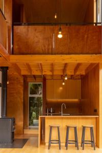 普纳凯基Punakaiki Forest Retreat的厨房设有木墙和带凳子的台面。