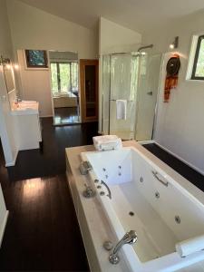 赫本温泉蓝崖度假酒店的大型浴室设有大型浴缸和淋浴。