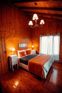 埃尔卡拉法特Paraiso Patagónico Bungalows and Apart Hotel的木制客房内的一间卧室配有一张大床